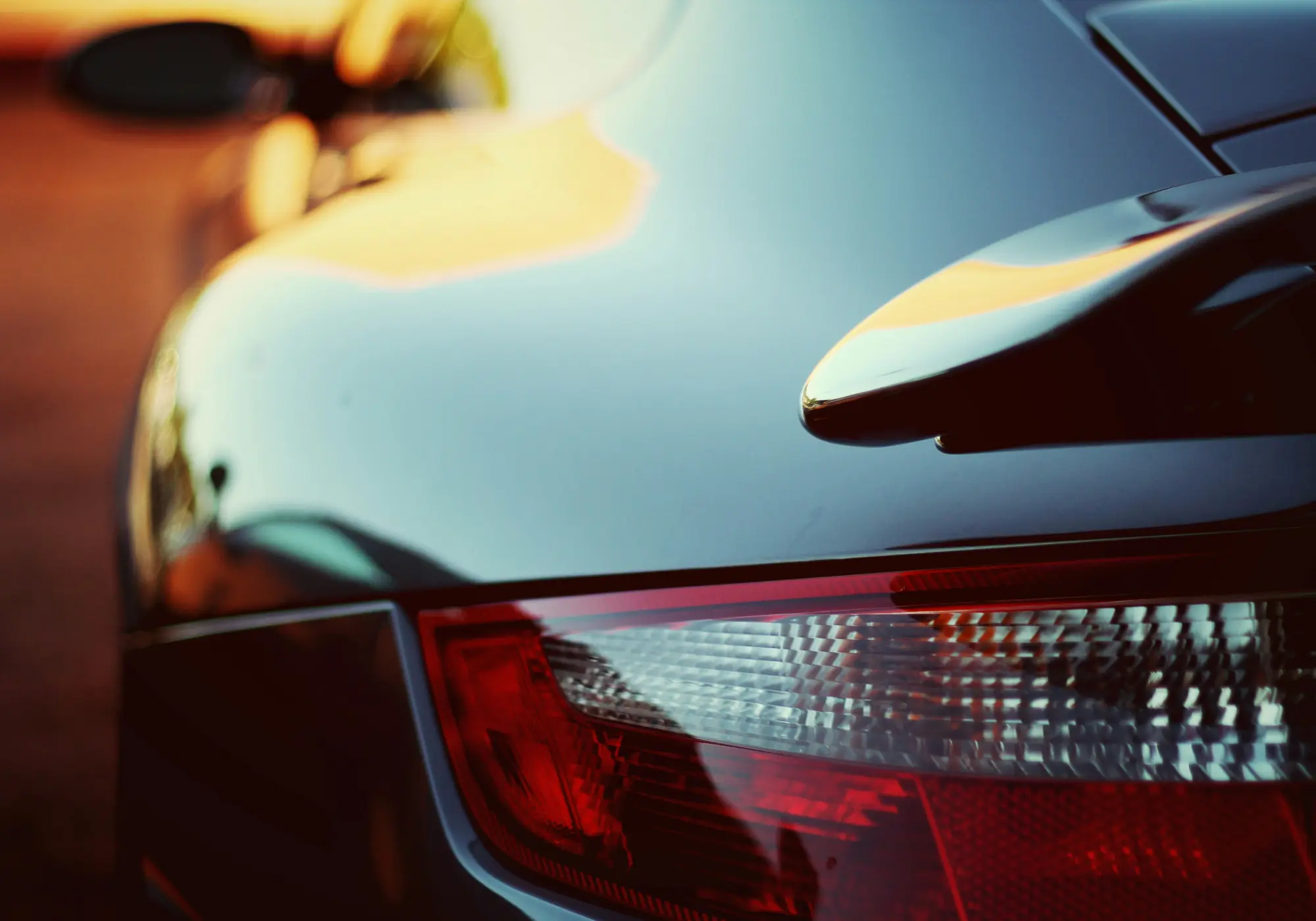 A image of a rear end of a sport car with sunset background